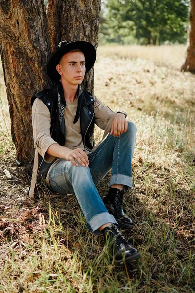 Yakışıklı genç adam rahat kıyafetler ve şık şapka açık havada poz 