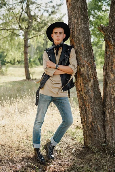 Yakışıklı genç adam rahat kıyafetler ve şık şapka açık havada poz 