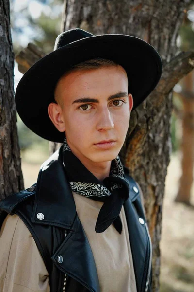 Yakışıklı genç adam rahat kıyafetler ve şık şapka açık havada poz 