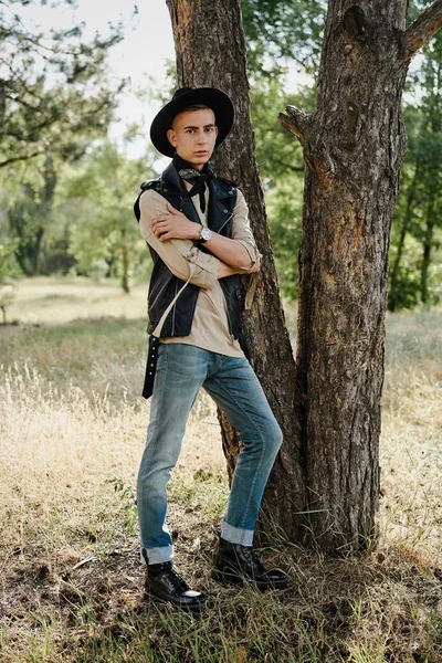 Yakışıklı genç adam rahat kıyafetler ve şık şapka açık havada poz 