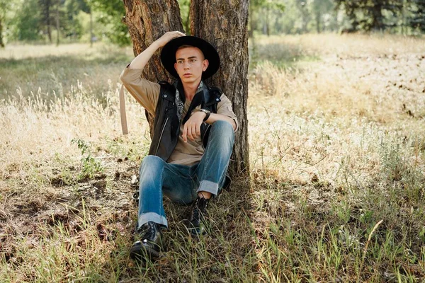 Yakışıklı genç adam rahat kıyafetler ve şık şapka açık havada poz 