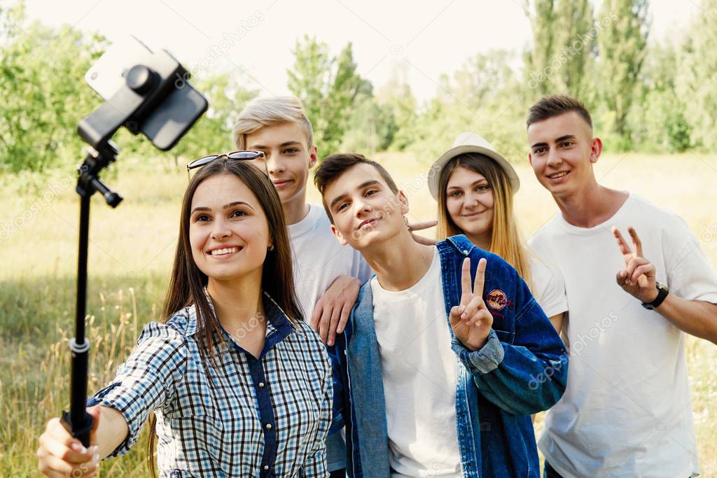  Group of young people taking a selfie outdoors, having fun         