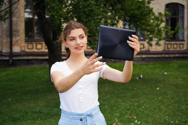  Genç beyaz güzel bir kadın selfie Park'ta alarak tablet pc ile          
