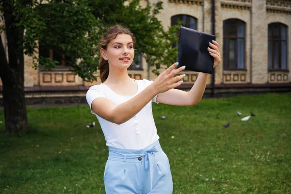  Genç beyaz güzel bir kadın selfie Park'ta alarak tablet pc ile          