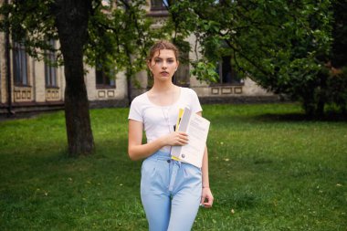  Genç kız öğrenci okul Courtyard ders kitabı ile       