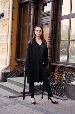 Sokakta poz siyah giysili güzel genç esmer kadın 