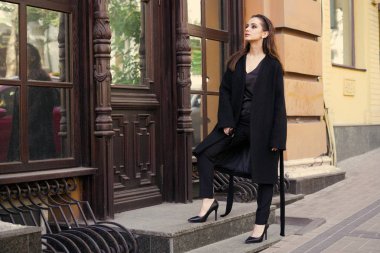 Sokakta poz siyah giysili güzel genç esmer kadın 