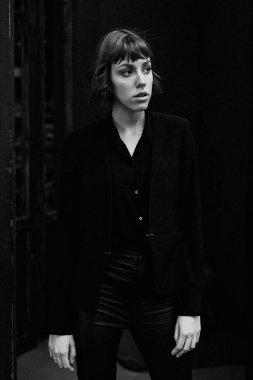 Poz şık siyah giysili genç kısa saçlı kadın              