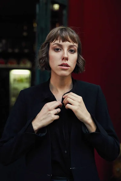 Young short haired woman in stylish black clothes posing