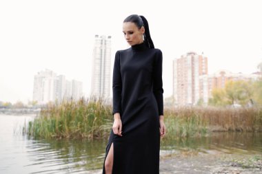 Açık havada poz siyah giysili genç ve güzel bir modeldir 