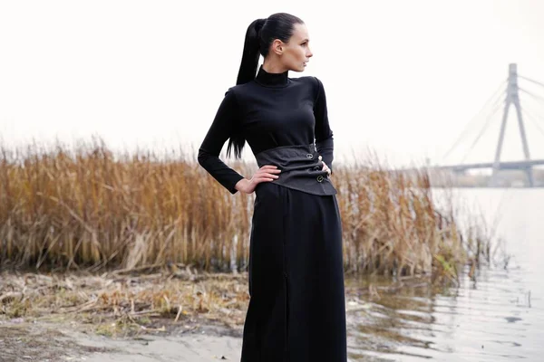 pretty young fashion model in black clothes posing outdoors