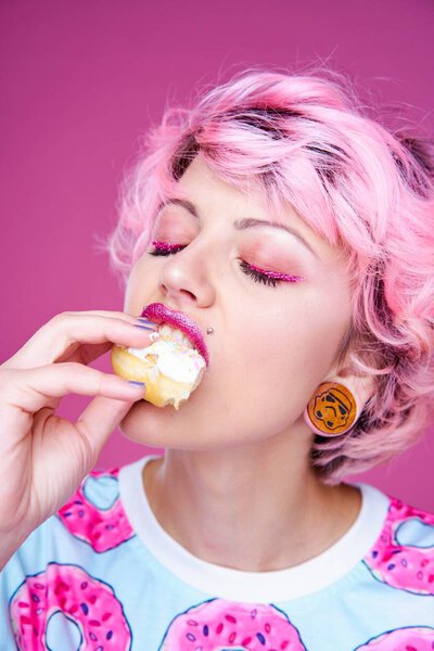 Милая женщина с розовыми волосами, поедающая пончик
 