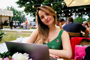 Young beautiful woman using laptop in outdoor cafe