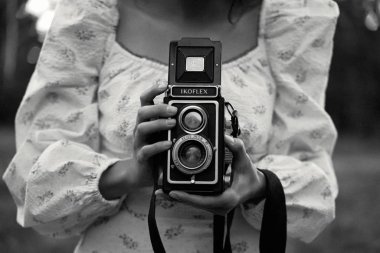 Dışarıda retro kameralı güzel genç bir kadın.