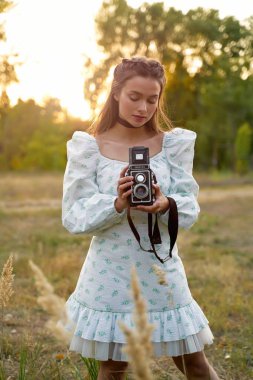 Dışarıda retro kameralı güzel genç bir kadın.