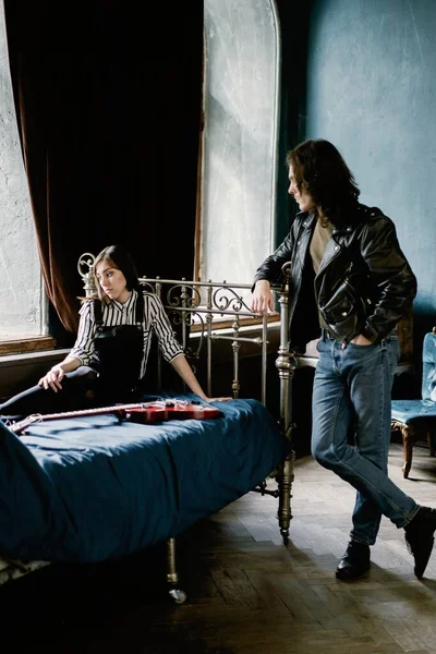 若いカップルがソファでギターを弾き ロイヤリティフリーのストック画像