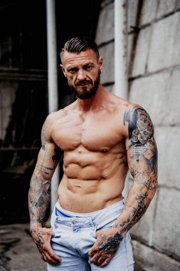 Genç üstsüz kaslı adam poz veriyor.