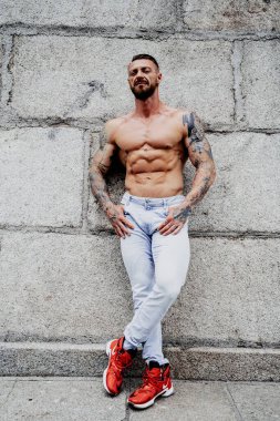 Genç üstsüz kaslı adam poz veriyor.