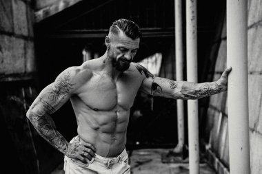 Genç üstsüz kaslı adam poz veriyor.