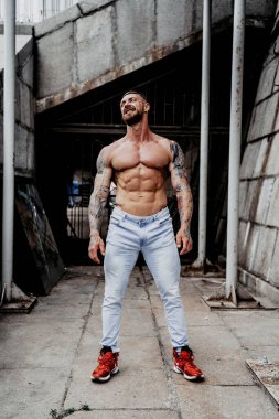 Genç üstsüz kaslı adam poz veriyor.