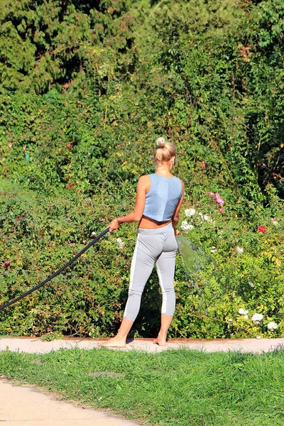 Hermosa chica regando las flores en el jardín botánico —  Fotos de Stock