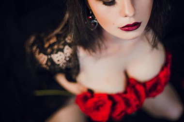 Genç üstsüz kadın kırmızı çiçeklerle poz veriyor.