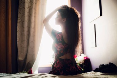 Genç ve güzel bir kadın yatakta oturuyor. 