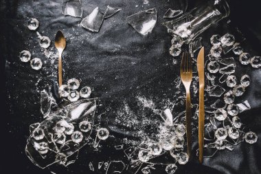 Altın kaplar, kristaller ve siyah zemin üzerindeki kırık camlar.