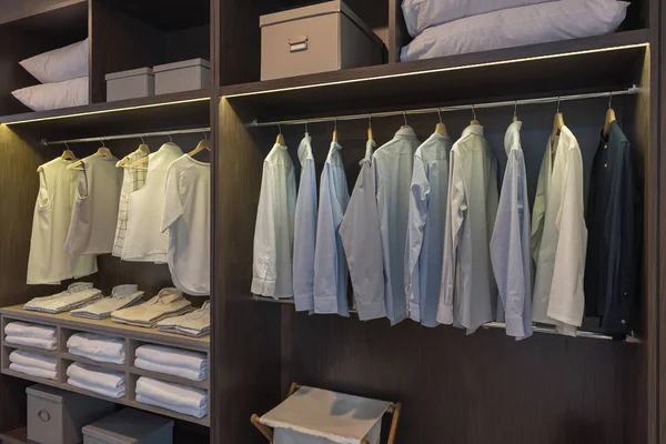 modern closet with clothes hanging on rail, wooden wardrobe, walk in closet interior design