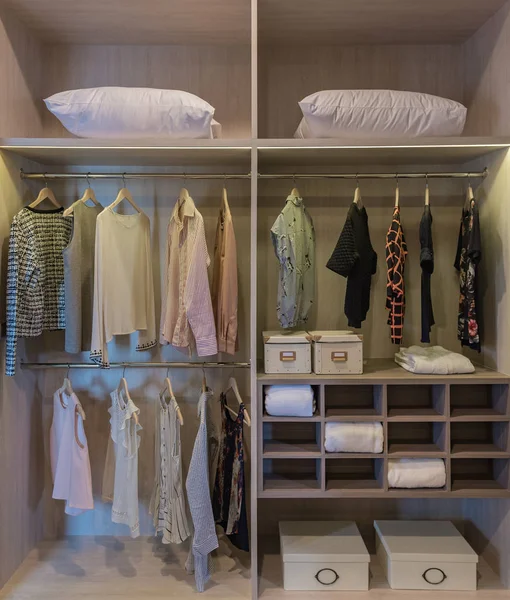 modern closet with clothes hanging on rail, wooden wardrobe, walk in closet interior design