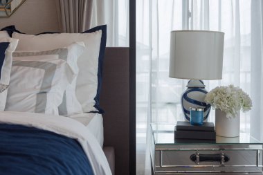 lüks yatak odasında çivit mavi tonu ile klasik lamba ve tablo tarafında, iç tasarım dekorasyon konsepti bitki vazo