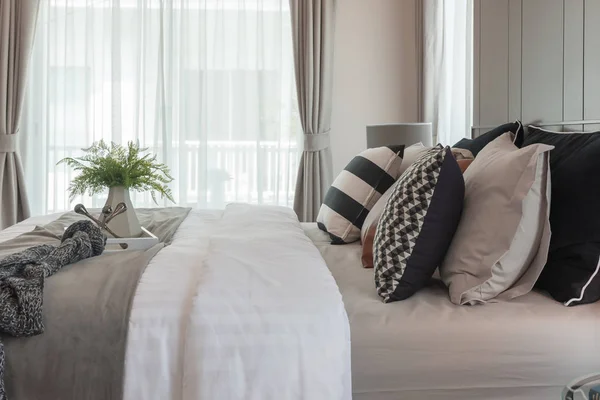 modern bedroom with plant in vase on tray and set of pillows, interior design concept