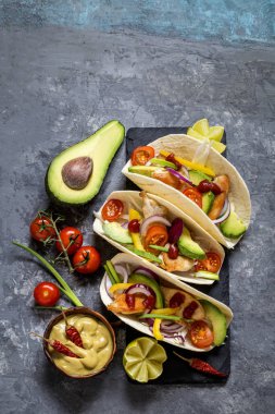 Meksika yemeği tacos, kızarmış tavuk, yeşil, avokado, biber, kırmızı lahana ve ekmeği koyu arka plan üzerinde avokado