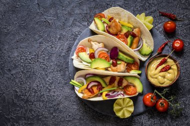 Meksika yemeği tacos, kızarmış tavuk, yeşil, avokado, biber, kırmızı lahana ve ekmeği koyu arka plan üzerinde avokado