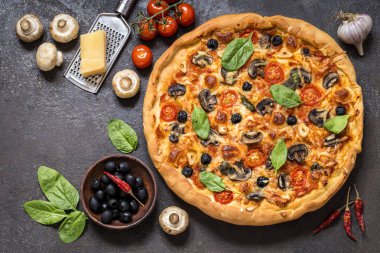 Pizza domates, peynir, mantar, zeytin ve ıspanak karanlık bir arka plan üzerinde
