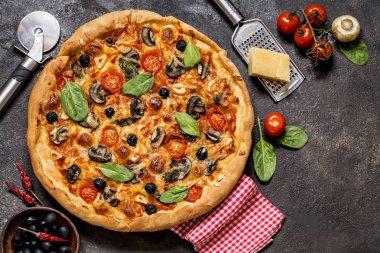Pizza domates, peynir, mantar, zeytin ve ıspanak karanlık bir arka plan üzerinde