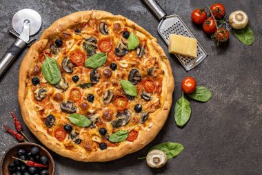 Pizza domates, peynir, mantar, zeytin ve ıspanak karanlık bir arka plan üzerinde