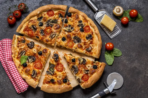 Pizza domates, peynir, mantar, zeytin ve ıspanak karanlık bir arka plan üzerinde