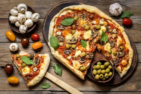 Pizza mantar, domates, zeytin ve Ispanaklı ve keçi peynirli ahşap arka plan üzerinde