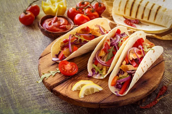 ahşap bir Tahta üzerinde tavuk, biber, domates, lahana ve salsa ile tacos Meksika gıda