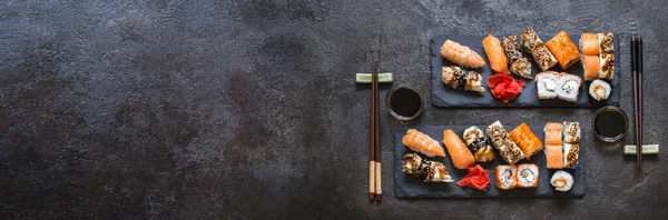 Suşi, pilav ve balıklı, soya sosu ve koyu taşlı arka plan.