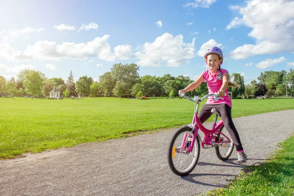 Lány lovaglás kerékpár sisakot. Kerékpáros park nyári. — Stock Fotó