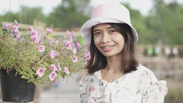 亚洲女人 身穿花纹衣服 喜欢旅行 戴着粉色帽子 看手镯 — 图库照片