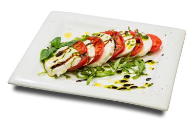 Caprese. Taze domates ve mozzarella peyniri ile iştah açıcı. Beyaz bir tabak ve beyaz bir arka plan üzerinde