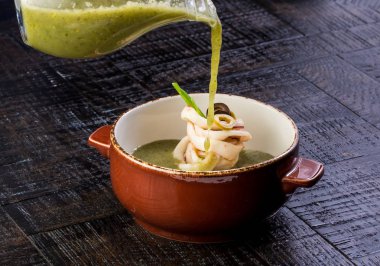 Ispanak kalamar çorbası. Ahşap bir masaya. Seramik kap içinde