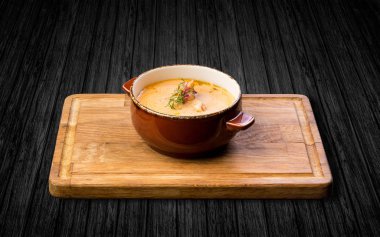 Ahşap bir masa üzerinde seramik bir tencerede karides çorbası