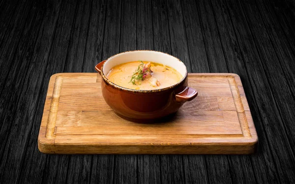 Ahşap bir masa üzerinde seramik bir tencerede karides çorbası