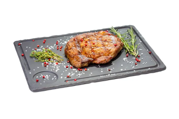 Domuz eti biftek dikdörtgen taş tabakta rosemary ile tuz ve baharatlar ile dekore edilmiş