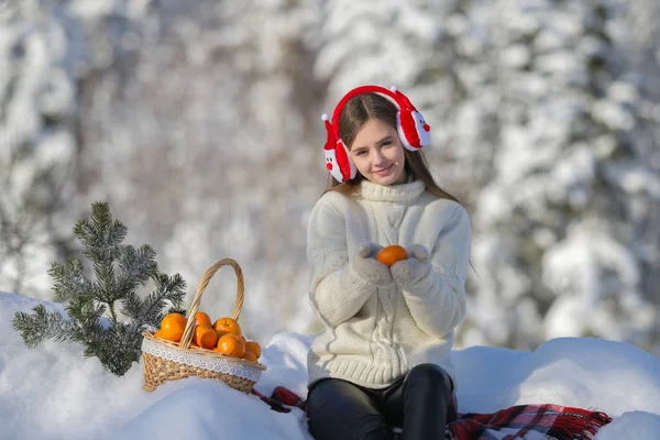 Genç bir kız kış orman kulaklık Noel Baba mandarin bir sepet ile içeri girer.