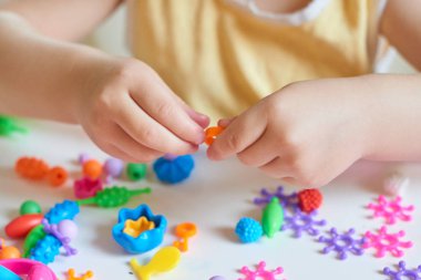 Çocuğun Ellerin masada renkli plastik tuğla ile oynarken kapatın. Eğleniyor ve parlak Oluşturucu tuğla dışında bina toddler. Erken öğrenme. Şerit arka plan. Oyuncaklar geliştirilmesi